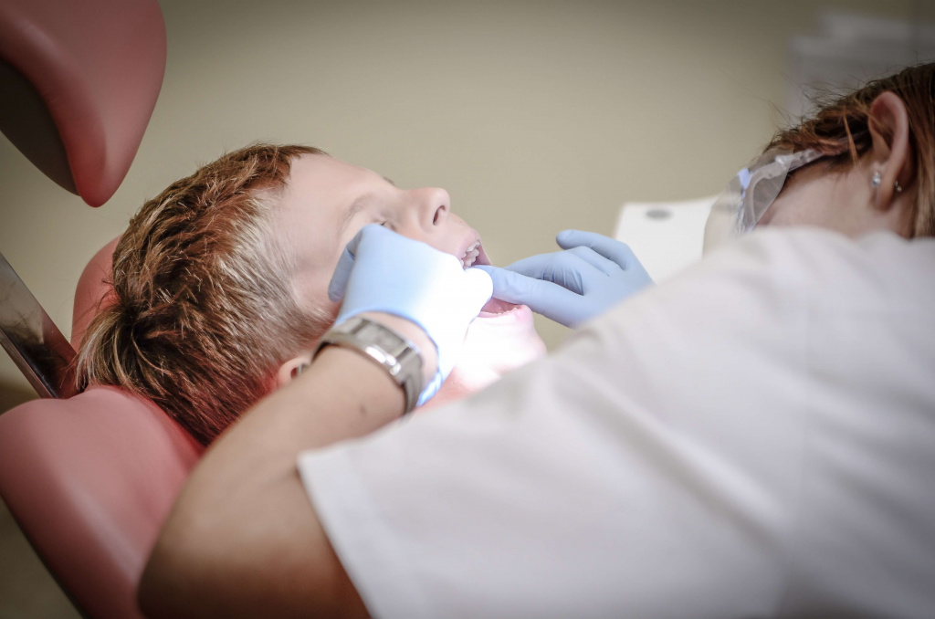 Cтоматолог осматривает двойные зубы у ребенка